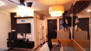 Un salon moderne avec un canapé, une table à manger sur laquelle reposent deux ordinateurs portables, un téléviseur et un ventilateur de plafond.