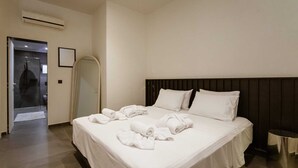 Ein Hotelzimmer mit einem großen Bett, einem Nachttisch, einem Spiegel und einer Klimaanlage.