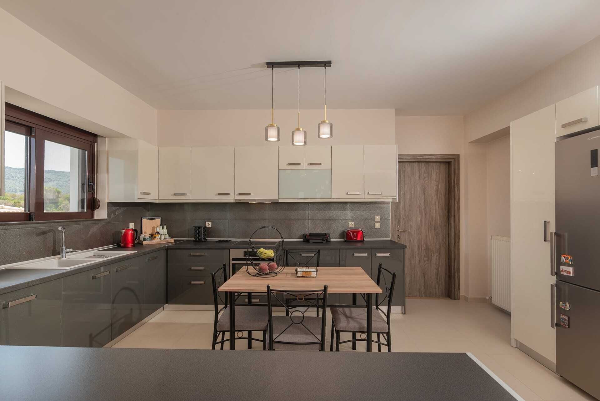 A modern kitchen with a central island, pendant lighting, and a built-in refrigerator.