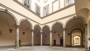 A spacious courtyard with multiple arches and columns, leading to a distant doorway. - Tower View Apartment (Firenze)