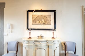 A room with a white console table, two chairs, a framed artwork above the table, and a wall-mounted telephone. - Tower View Apartment (Firenze)