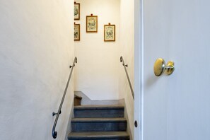A staircase with handrails, a door with a brass handle, and framed artwork on the wall. - Tower View Apartment (Firenze)