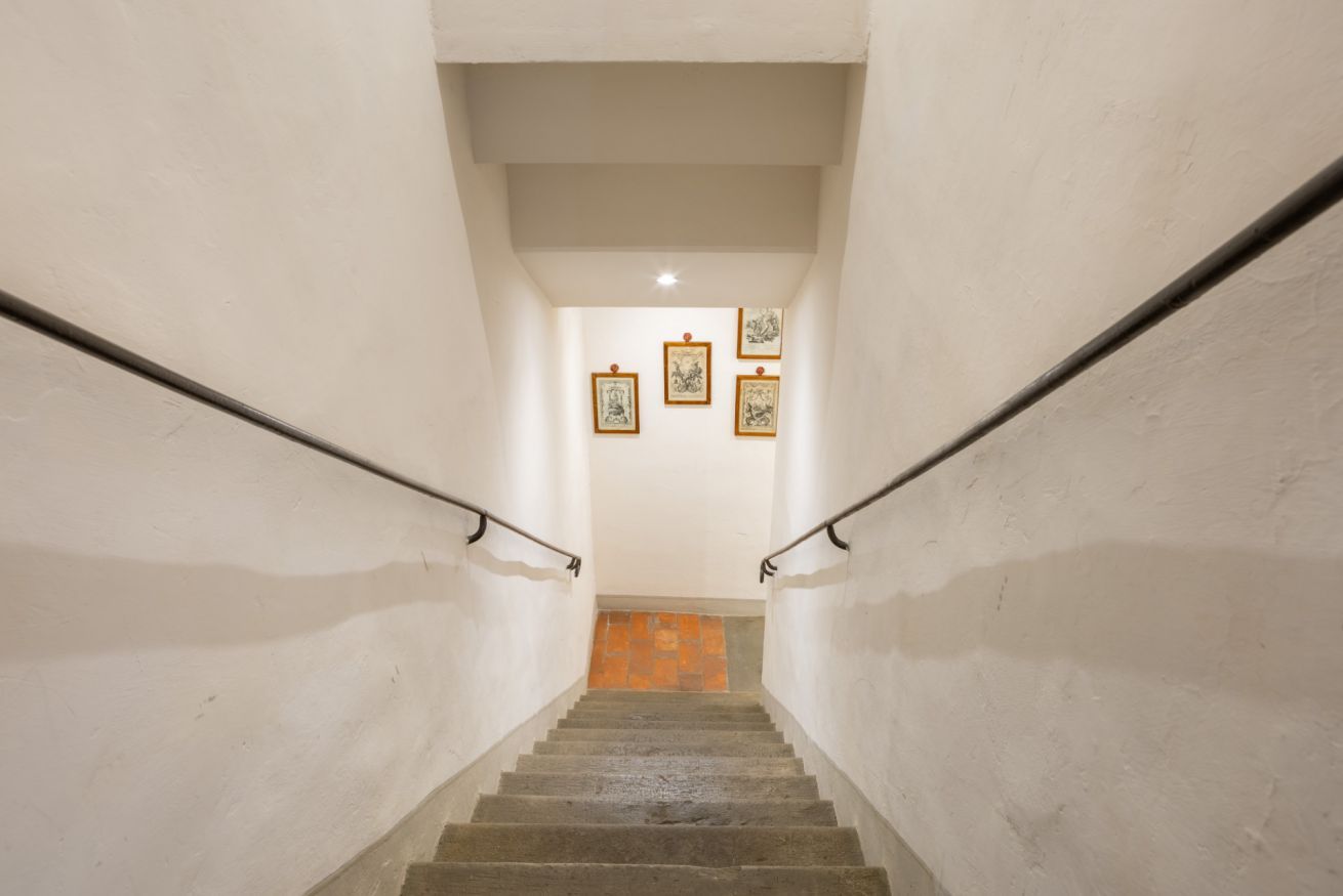 A staircase with a handrail on both sides, leading to a landing with three framed pictures on the wall.