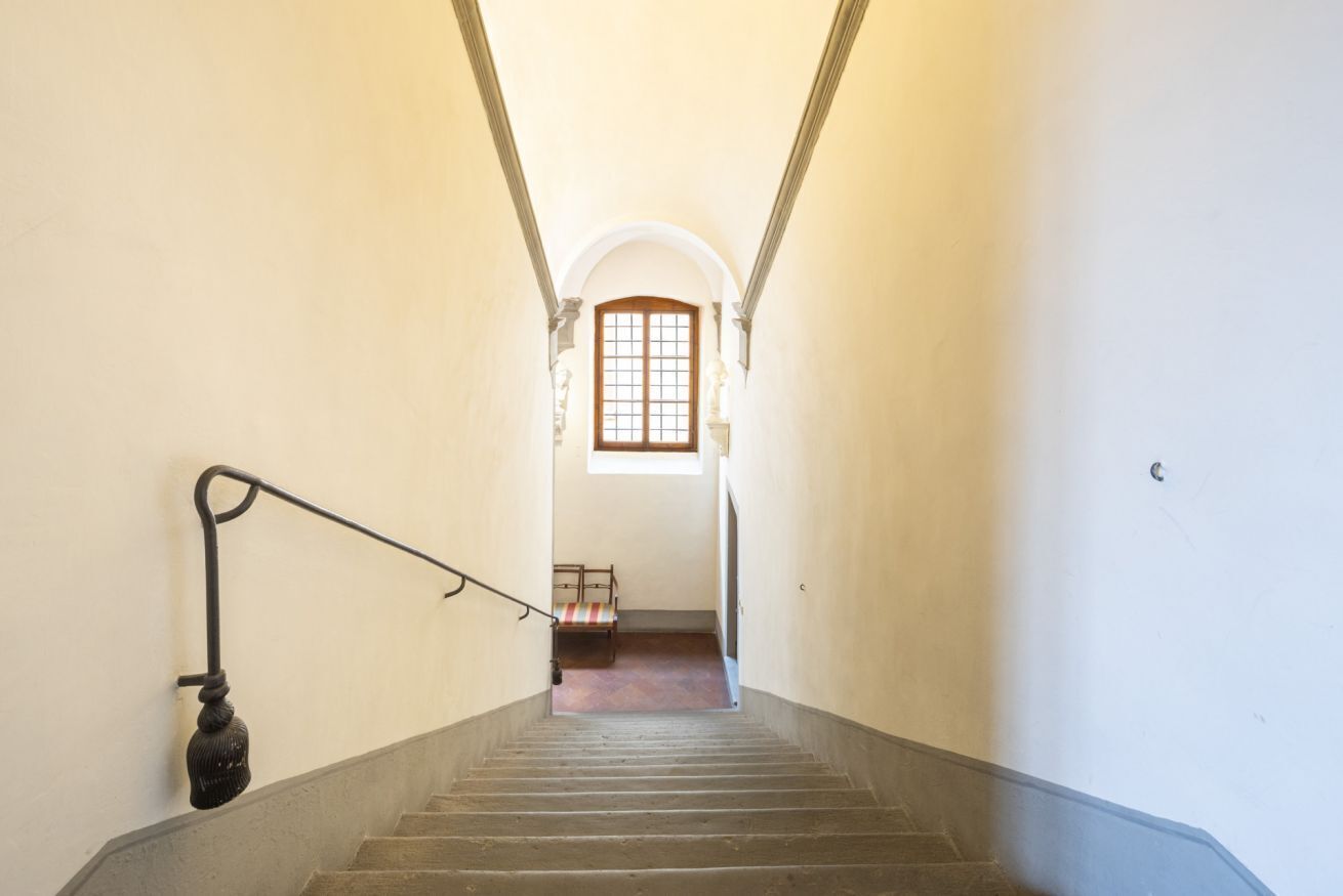 Un escalier menant à une pièce dotée d’une fenêtre et d’un lit.