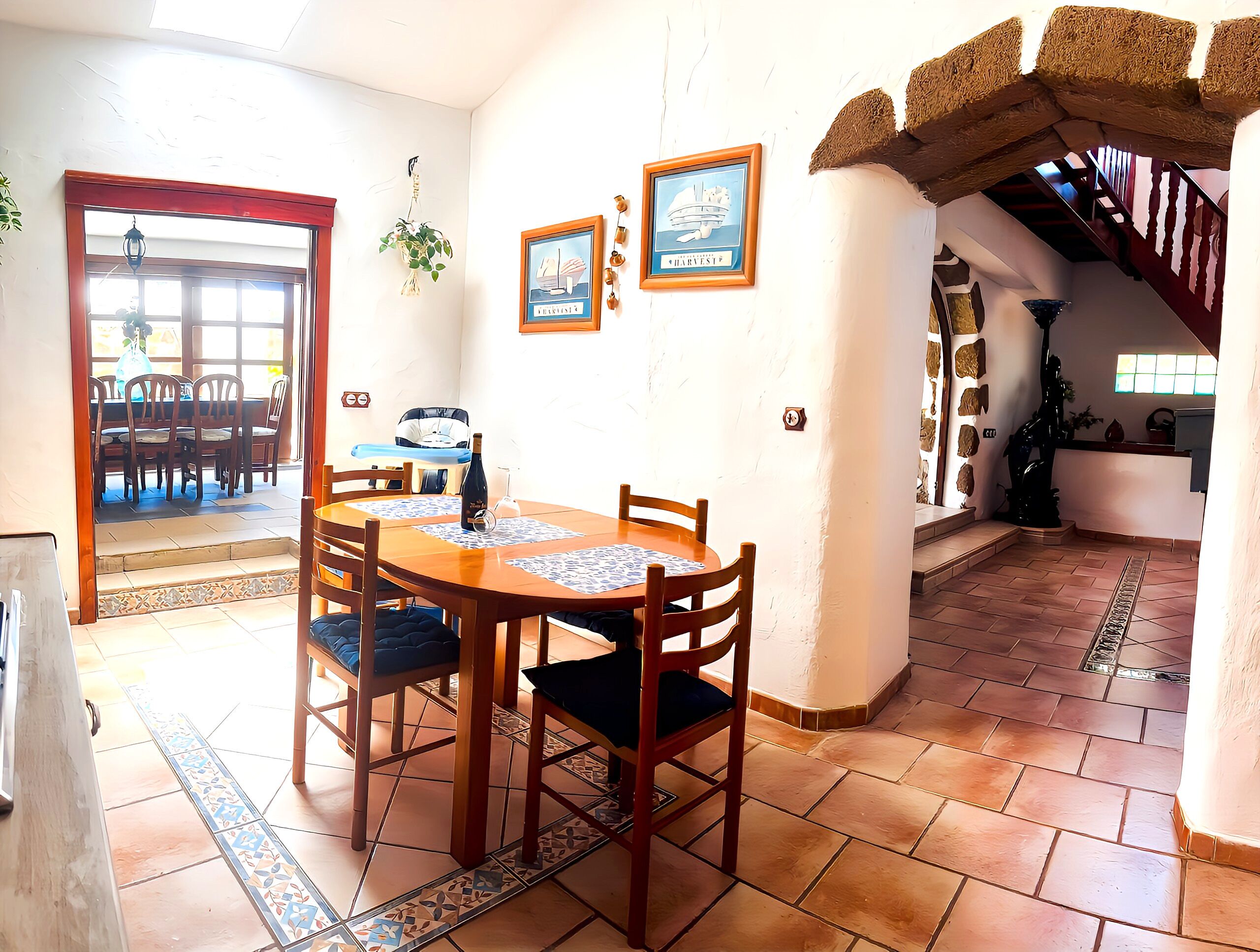 Un coin repas avec une table et des chaises en bois, une bouteille de vin et une horloge au mur.