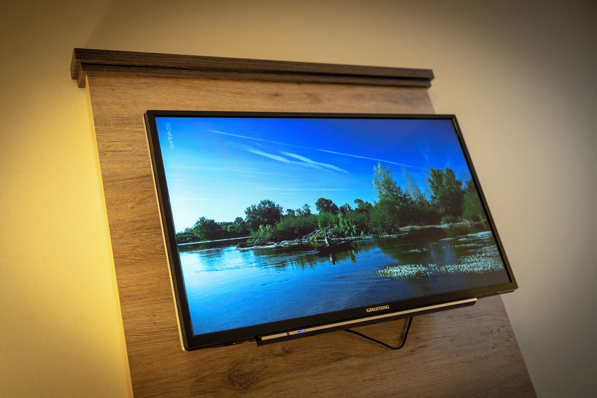 A television mounted on a wooden wall, displaying a scenic outdoor image.