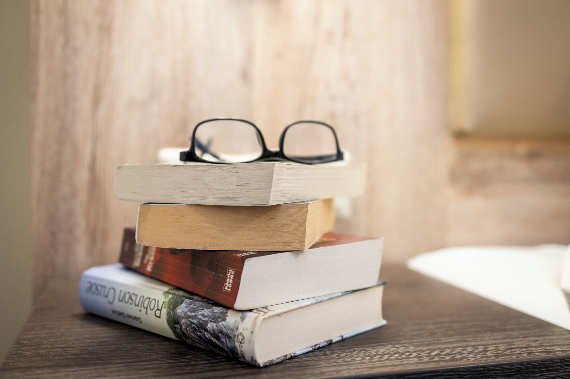 Un montón de libros con gafas encima, sobre una superficie de madera.