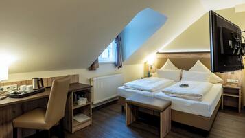 Ein Hotelzimmer mit Stockbett, Schreibtisch mit Stuhl, einem kleinen Tisch und einem an der Wand montierten Fernseher.