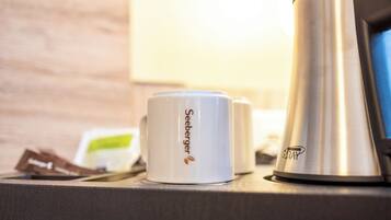 Eine Kaffeemaschine und zwei weiße Tassen mit dem Seeburger Logo auf einer Arbeitsplatte.