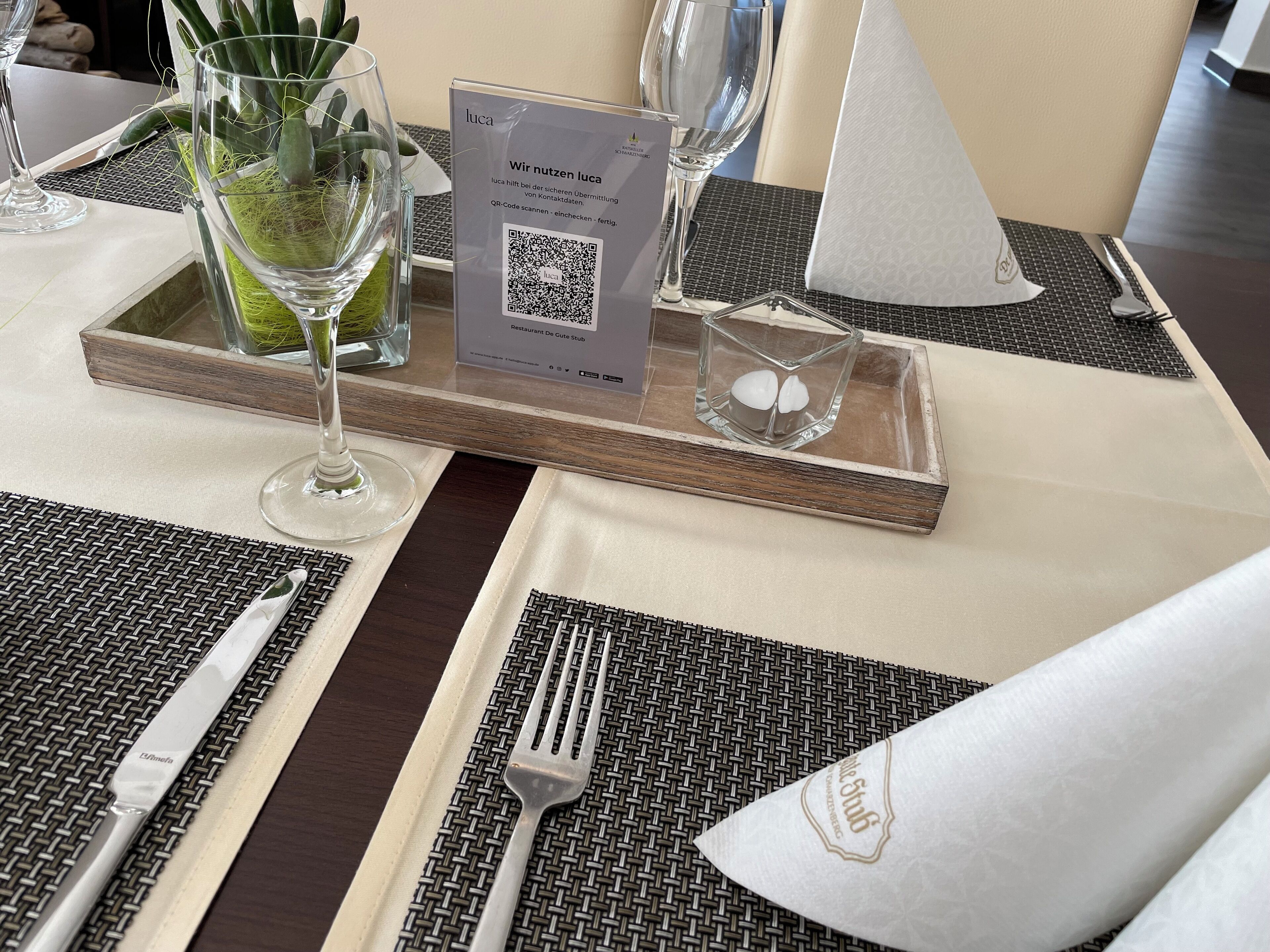 Una mesa de comedor dispuesta con un código QR para registro sin contacto, un menú y una vela pequeña.