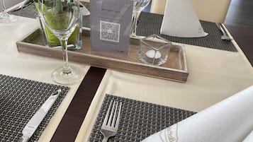 Una mesa de comedor dispuesta con un código QR para registro sin contacto, un menú y una vela pequeña.