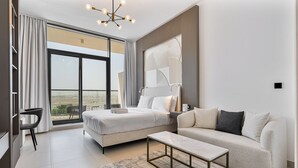 Quarto de hotel moderno com uma cama grande, um sofá, uma mesa de centro e vista para a cidade.