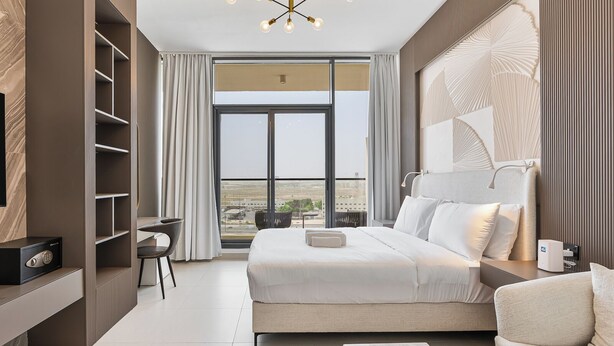 Quarto de hotel moderno com uma cama grande, uma escrivaninha e vista para a cidade.