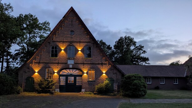 A brick building with a triangular roof, a central entrance with a door, and multiple windows. - Modern vacation apartment, Prinzhöfte up to 6 persons Price is for the whole apartment (Prinzhöfte, OT Klein Henstedt)