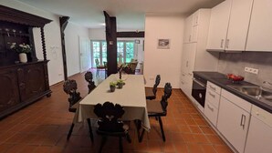A spacious kitchen with a dining area, featuring a large table, chairs, and cabinets. - Modern vacation apartment, Prinzhöfte up to 6 persons Price is for the whole apartment (Prinzhöfte, OT Klein Henstedt)