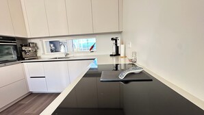 A modern kitchen with white cabinets, a black countertop, and a built-in oven.