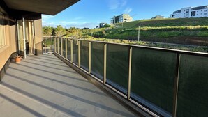 A balcony with a view of a green landscape and modern buildings.