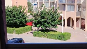 A balcony with a table and chairs, overlooking a residential area with buildings and greenery.