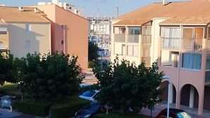 A residential area with parked cars, a building with a tiled roof, and greenery.