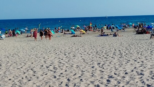 A sandy beach with footprints and people in the distance.