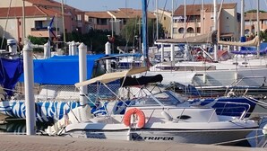 A marina with boats docked, a lifebuoy, and buildings in the background.
