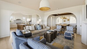 A spacious living area with a sofa, coffee table, and dining set. There are arched doorways leading to other rooms.