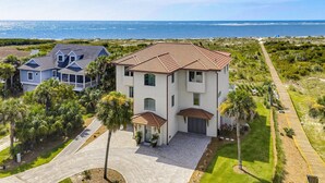 A two-story house with a tiled roof, a driveway, and a view of the ocean.