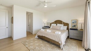 A bedroom with a bed, bedside tables, a ceiling fan, and a door.