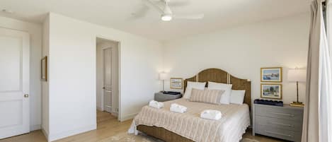 A bedroom with a bed, bedside tables, a ceiling fan, and a door.