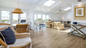 A spacious living area with wicker furniture, a piano, and a view of the outdoors. - 715 Winter Trout Road (Fripp Island)