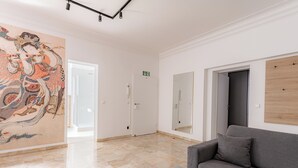 Um quarto espaçoso com um grande mural, um sofá cinza e um painel de madeira na parede.