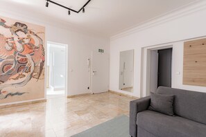 Ein geräumiges Zimmer mit einer großen Wandmalerei, einem grauen Sofa und einer Holzwand.
