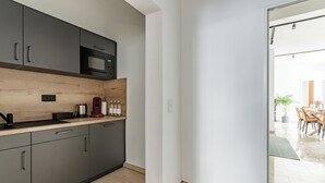 Cozinha moderna com armários cinza, bancada de madeira, micro-ondas e máquina de café.