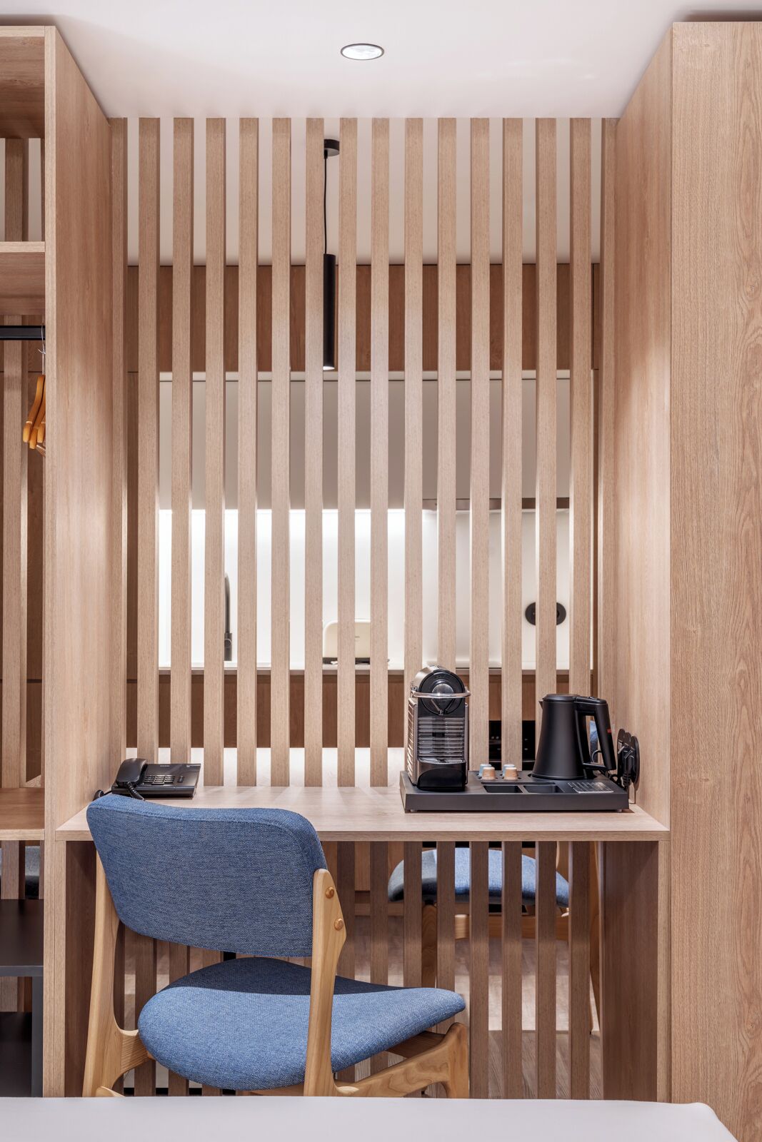 Een moderne kamer met een houten lambrisering, een bureau met een koffiezetapparaat en een stoel.