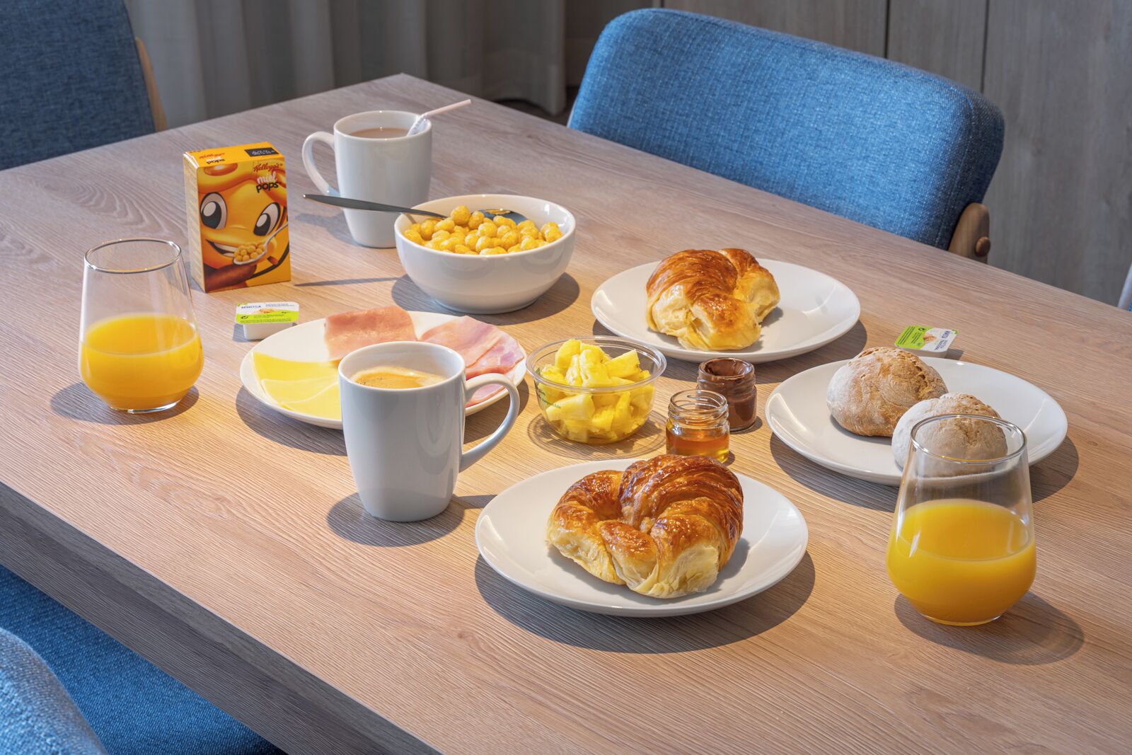 A breakfast table with various food items, including croissants, fruit, and beverages.