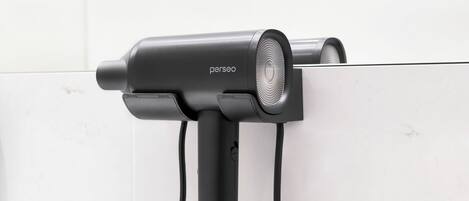 A hair dryer mounted on a wall with a cord.