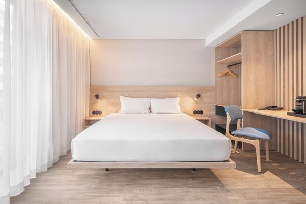 Une chambre d’hôtel moderne avec un grand lit, un bureau avec une chaise et une armoire.