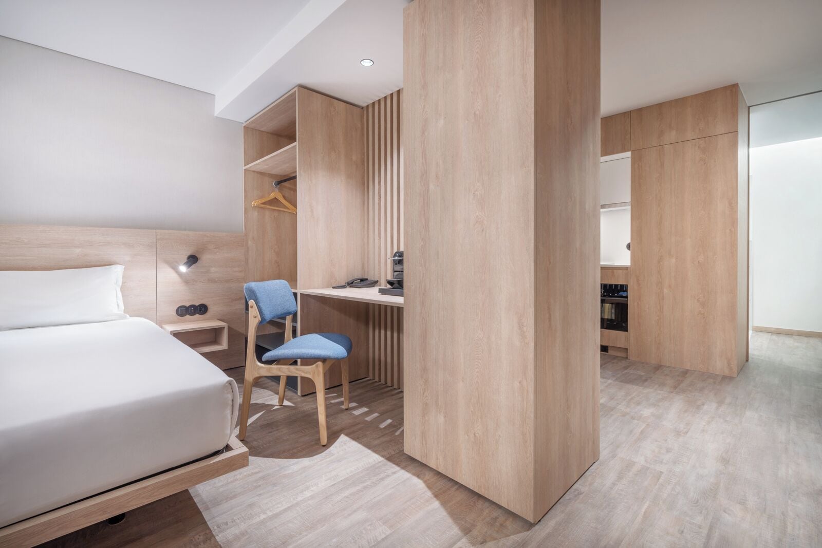 Una habitación de hotel moderna con cama, escritorio, silla y armario.