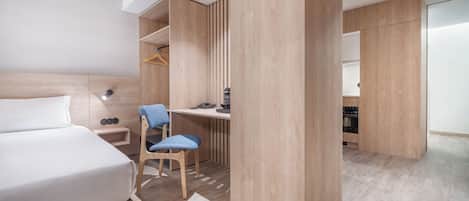 A modern hotel room with a bed, a desk, a chair, and a wardrobe.