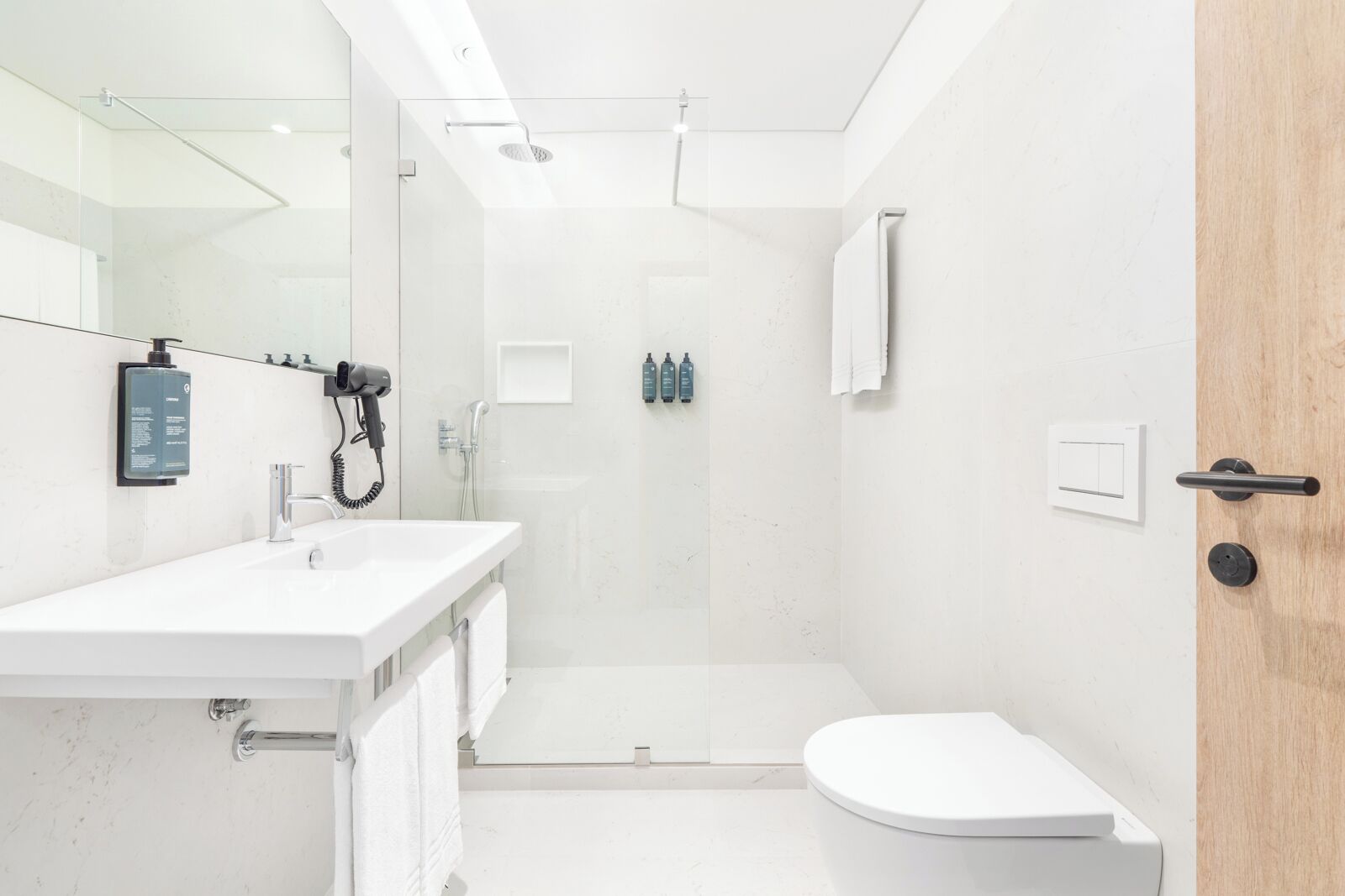 A modern bathroom with a white sink, mirror, and toilet.