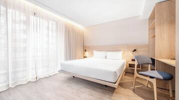 Quarto de hotel moderno com uma cama grande, uma escrivaninha com cadeira e um guarda-roupa.