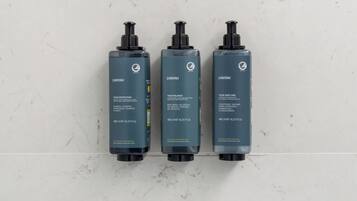 Tre flaconi di prodotti per la cura dei capelli Anyah su una superficie in marmo.