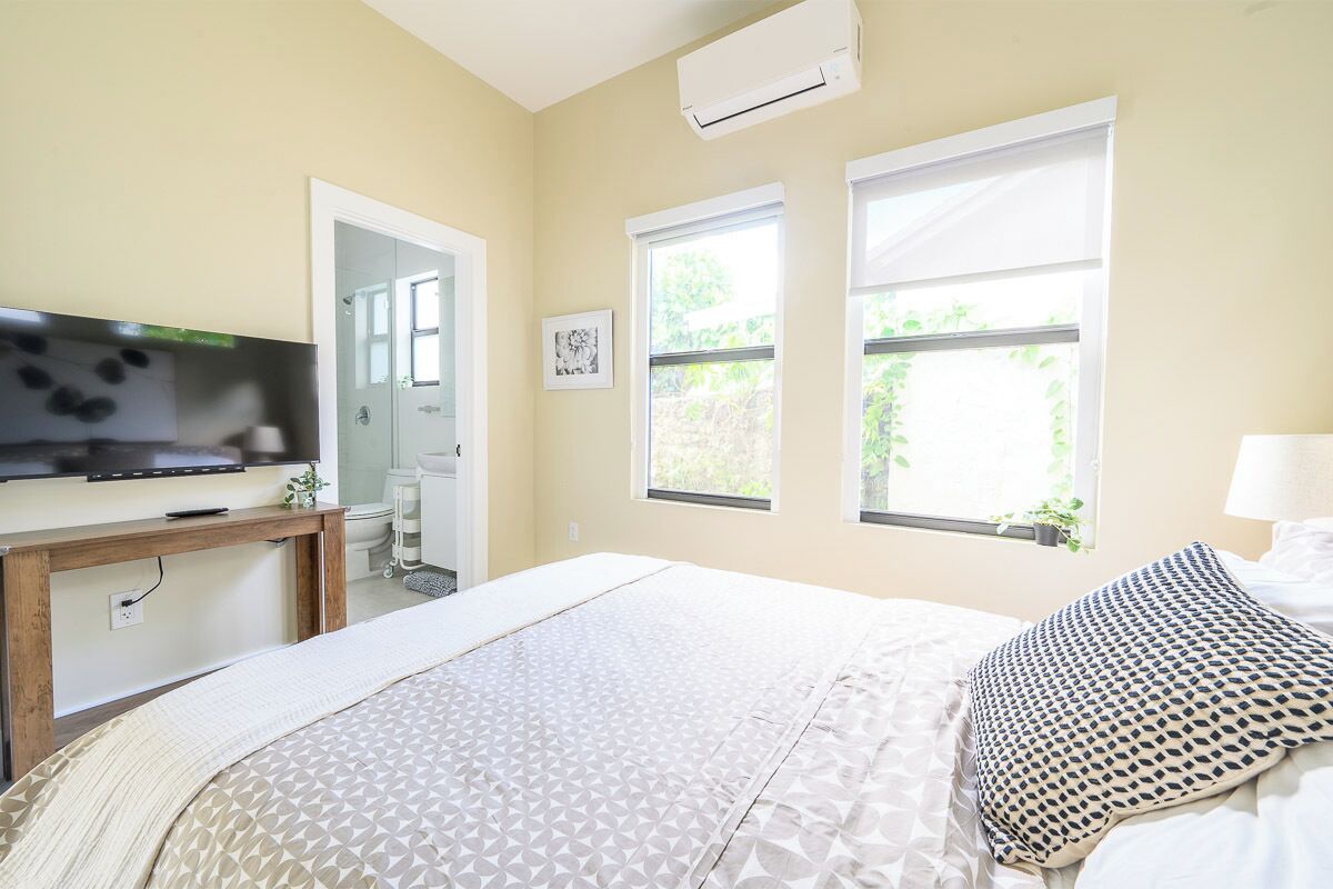 Ein Schlafzimmer mit Bett, Fernseher, Schreibtisch und Fenster.