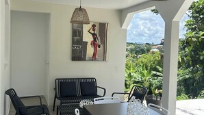 A dining area with a table, chairs, and a hanging light fixture. - NEW: THE IVORY 3-BEDROOM VILLA (Gros Morne)
