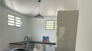 A modern kitchen with a central island, two white bar stools, a pendant light, and a large mirror. - NEW: THE IVORY 3-BEDROOM VILLA (Gros Morne)