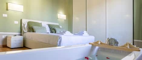 A modern bedroom with a large bed, a bedside table, a nightstand, a built-in bathtub with rose petals, and a wardrobe.