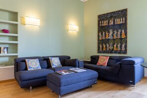 Ein modernes Wohnzimmer mit Ecksofa, Hocker und einem großen Wandbild.