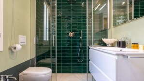 Ein modernes Badezimmer mit einer einachigen Duschkabine, einer weißen Toilette und einem Waschbecken mit Spiegel darüber.