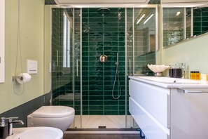Une salle de bain moderne avec une douche à parois de verre, des toilettes blanches et un lavabo avec un miroir au-dessus.