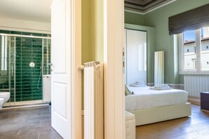 Une chambre avec un lit, une salle de bain avec une douche et une vue sur les bâtiments environnants.